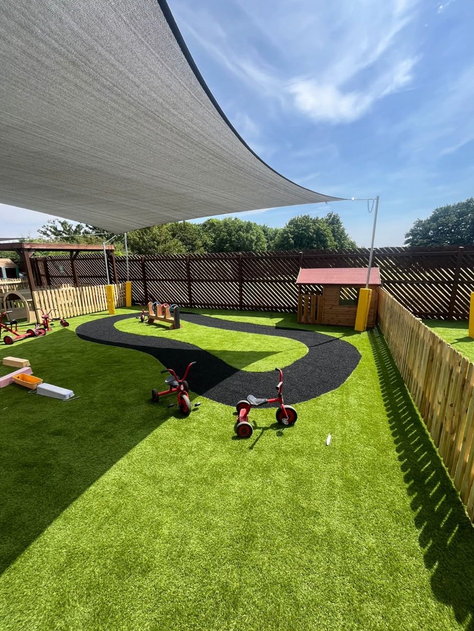 A nursery play area with a trike track on artificial grass
